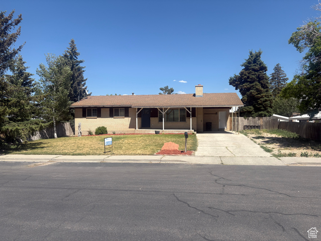 Ranch-style home with driveway, a carport, and a chimney