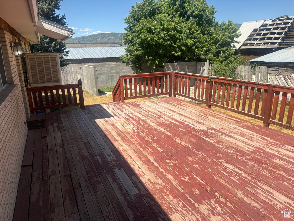 Wooden deck with a fenced backyard and a mountain view