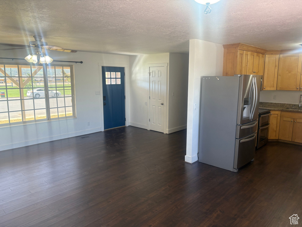 Kitchen with appliances with stainless steel finishes, a textured ceiling, dark wood-style floors, dark countertops, and ceiling fan
