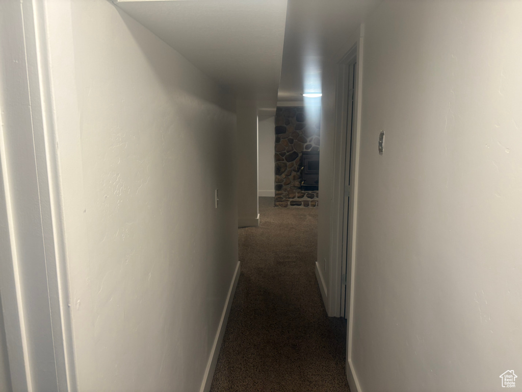 Corridor featuring dark carpet and baseboards