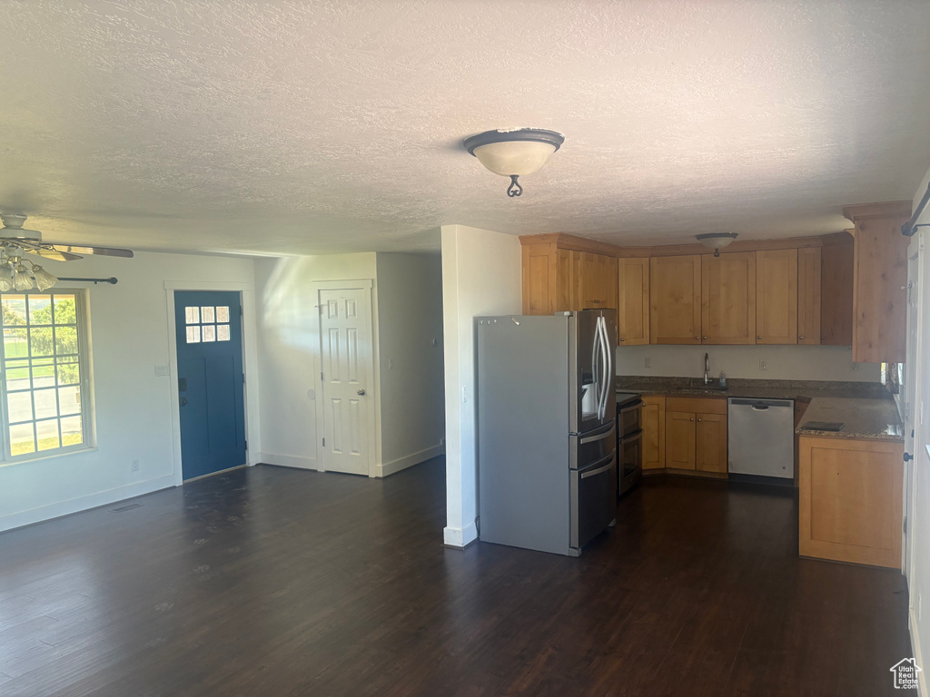 Kitchen featuring stainless steel appliances, dark wood-type flooring, a textured ceiling, a ceiling fan, and open floor plan