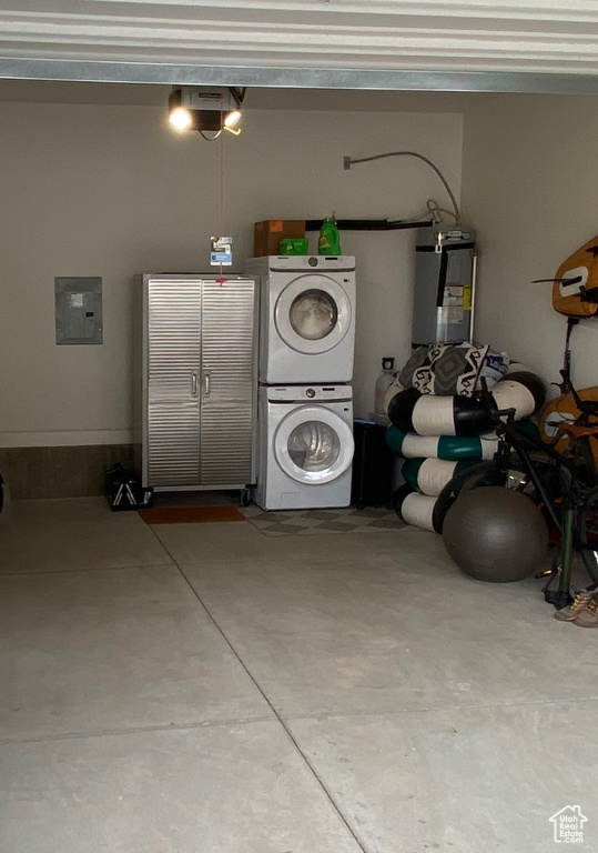 Garage featuring stacked washer / drying machine, a garage door opener, electric panel, and electric water heater