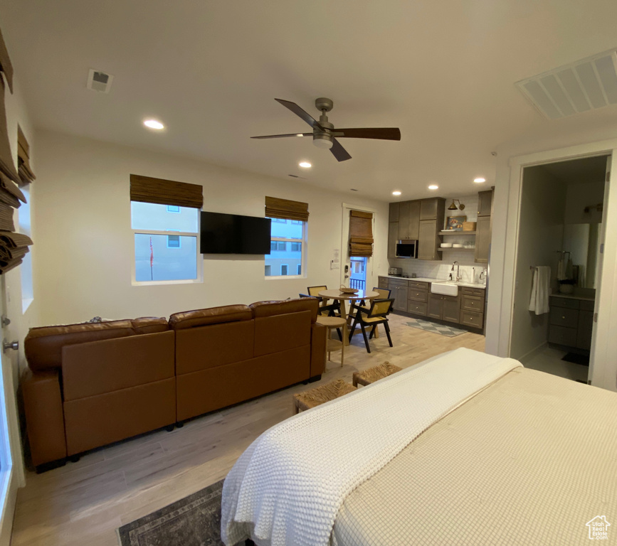 Bedroom with light wood finished floors, recessed lighting, ensuite bath, and a ceiling fan