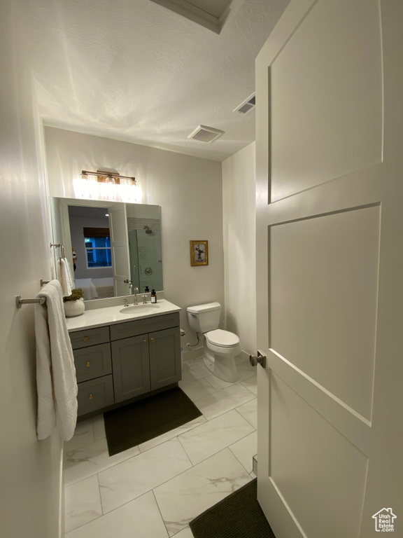Bathroom with marble finish flooring, vanity, a textured ceiling, and a shower