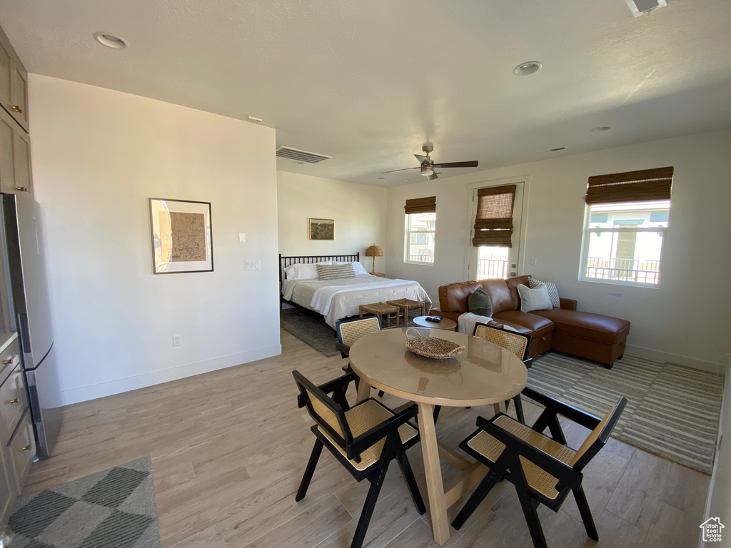 Bedroom with freestanding refrigerator, light wood-style flooring, and a ceiling fan