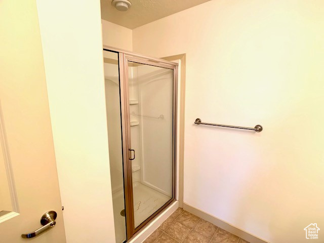 Full bath with a shower stall and baseboards