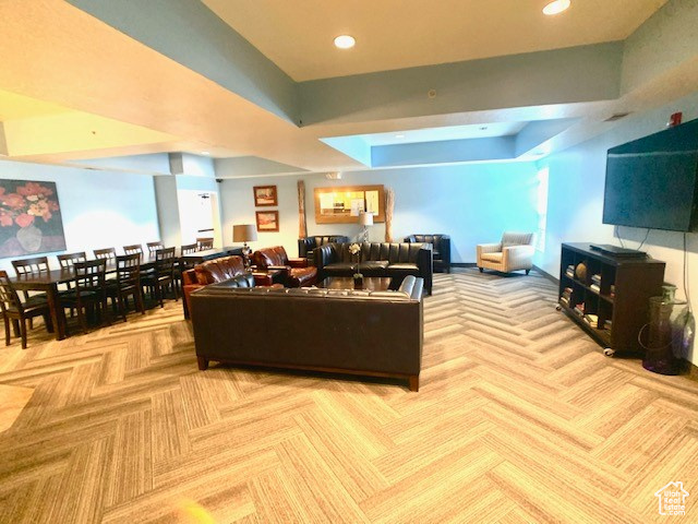 Carpeted living area with recessed lighting and a tray ceiling