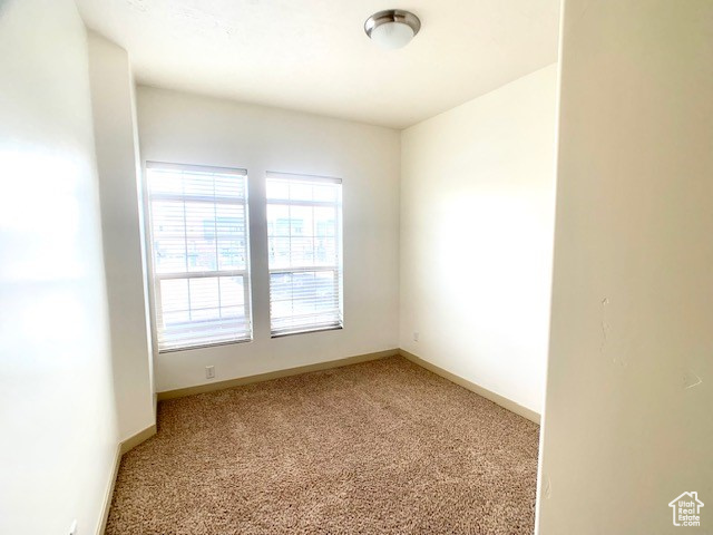 Spare room featuring light colored carpet and baseboards