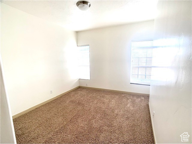 Carpeted spare room with baseboards
