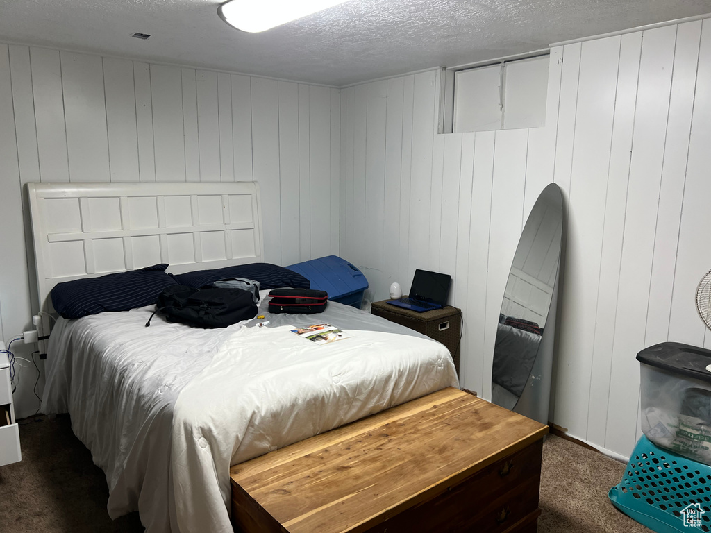 Bedroom featuring dark carpet and a textured ceiling