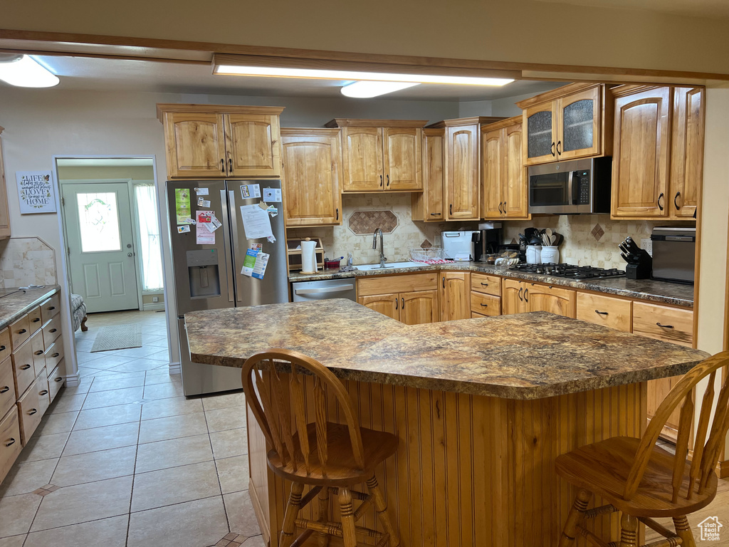 Kitchen with appliances with stainless steel finishes, a kitchen breakfast bar, and decorative backsplash