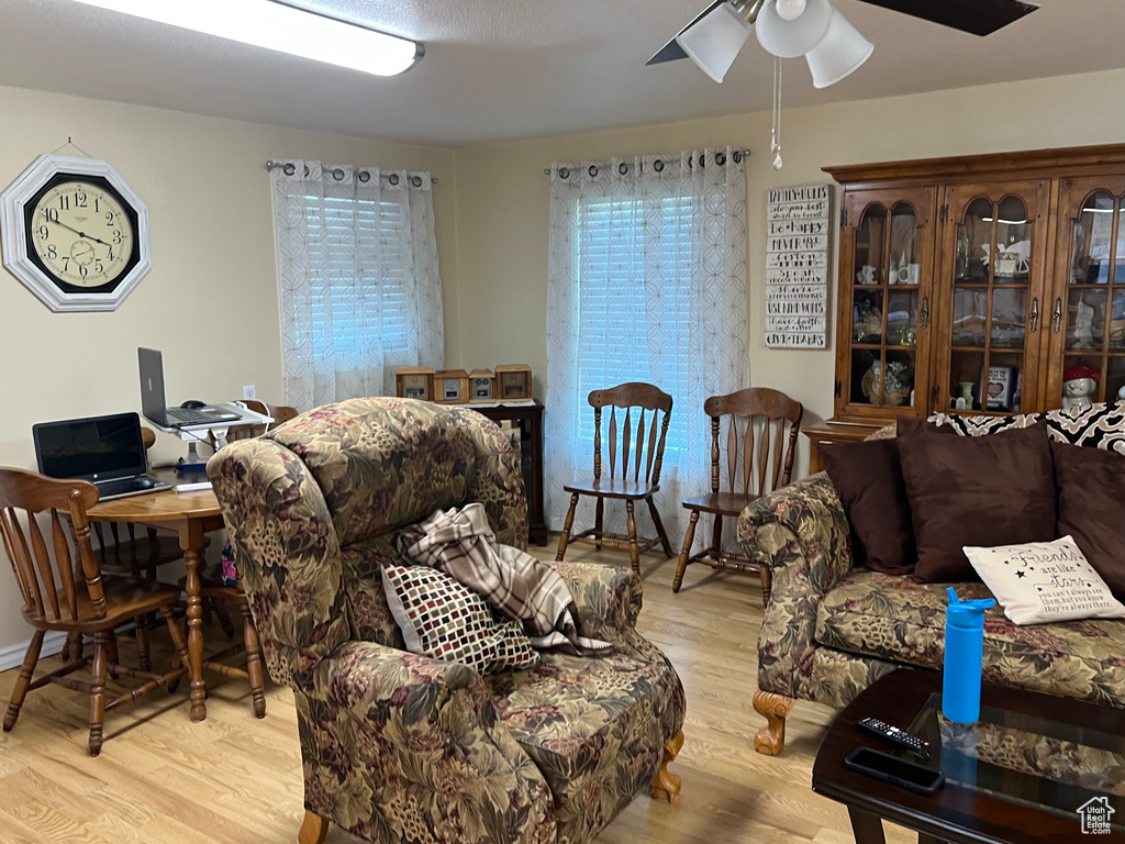 Living area with a ceiling fan, wood finished floors, and an office area