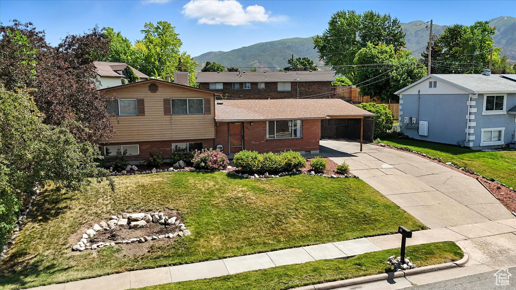 Split level home with driveway, a mountain view, a front yard, and brick siding