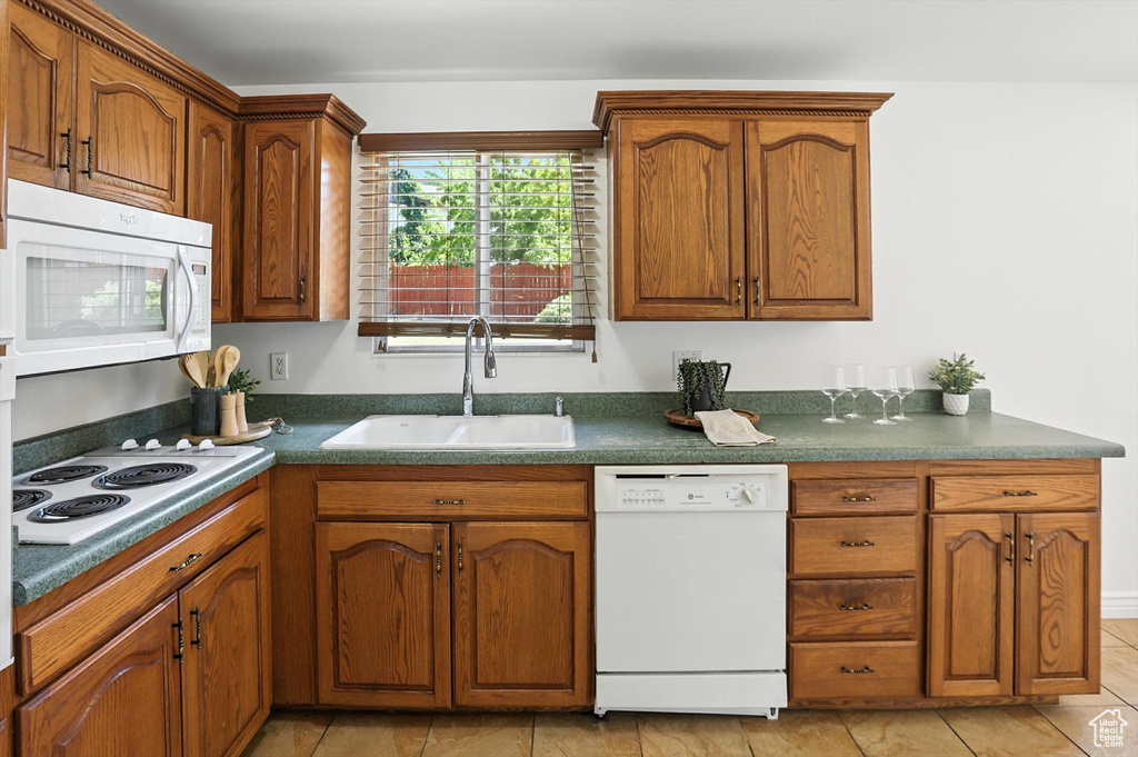 Kitchen with white appliances, brown cabinets, and dark countertops