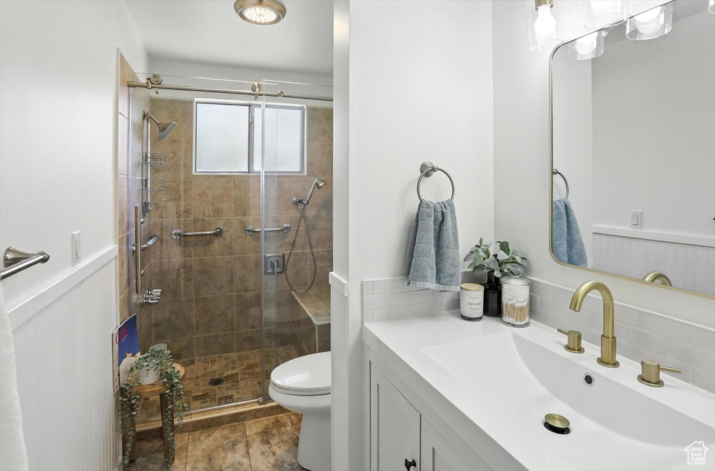 Bathroom featuring a stall shower, vanity, and wainscoting