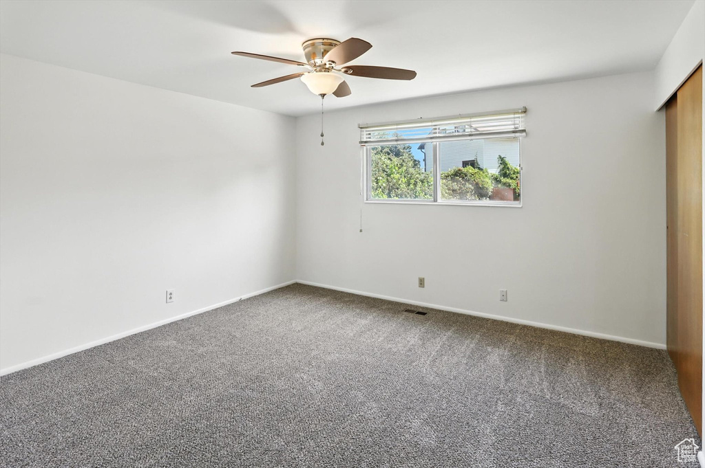 Unfurnished room featuring ceiling fan and carpet