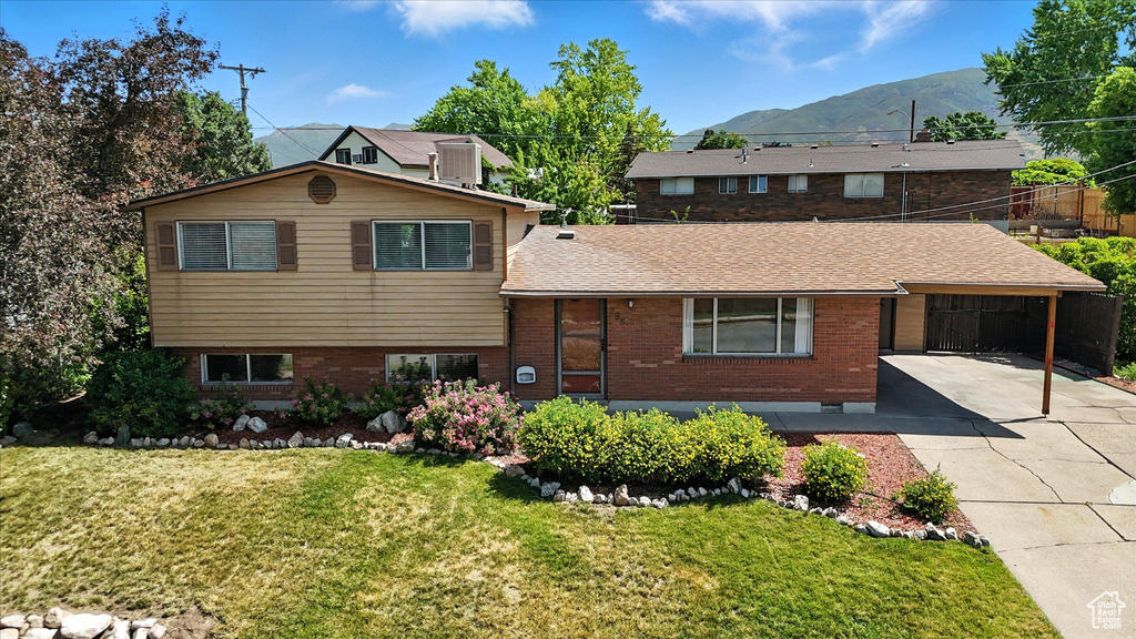 View of front of home with concrete driveway, a mountain view, brick siding, a front lawn, and an attached carport
