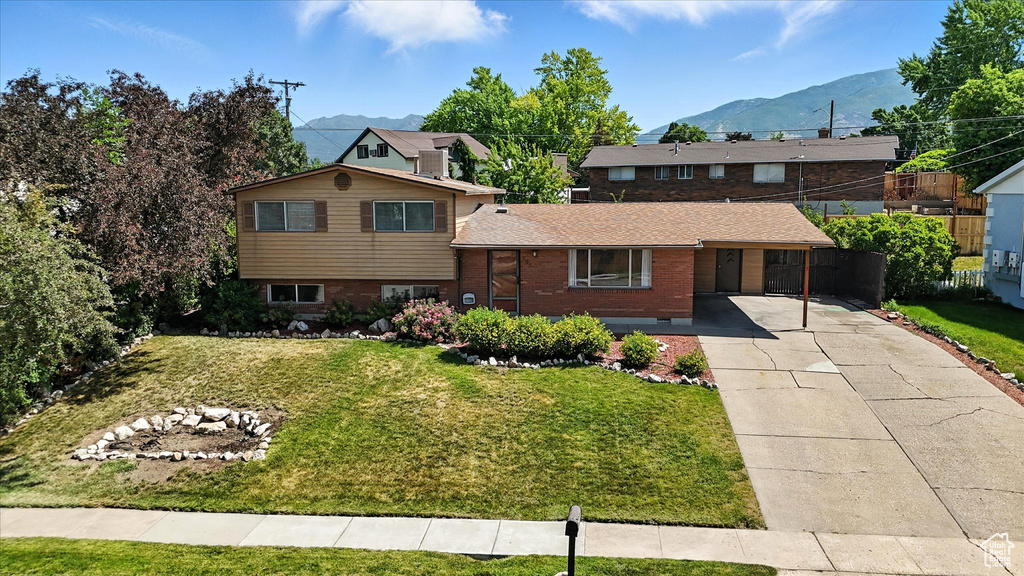 View of front of house with concrete driveway, a mountain view, and brick siding