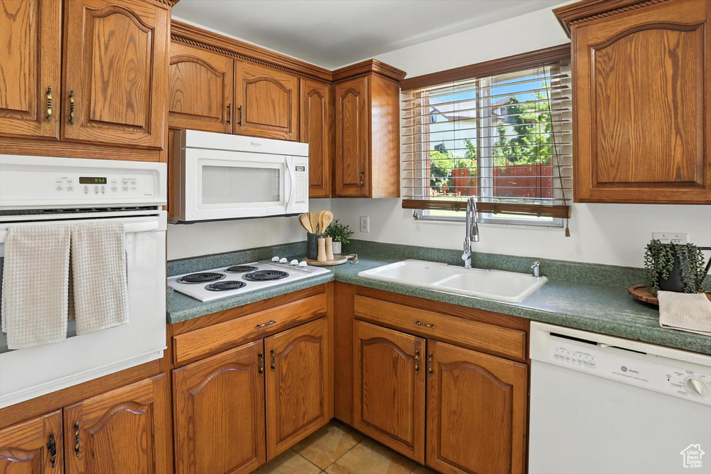 Kitchen featuring white appliances, brown cabinets, and light tile patterned floors