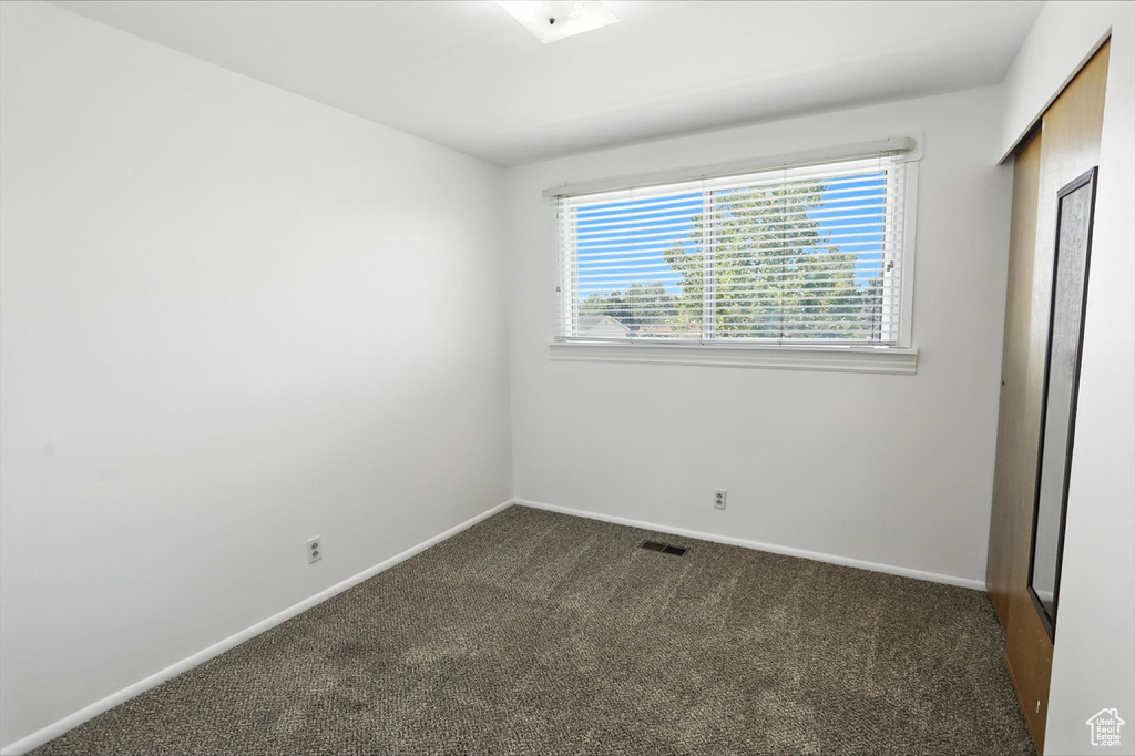 Unfurnished bedroom featuring dark carpet and baseboards