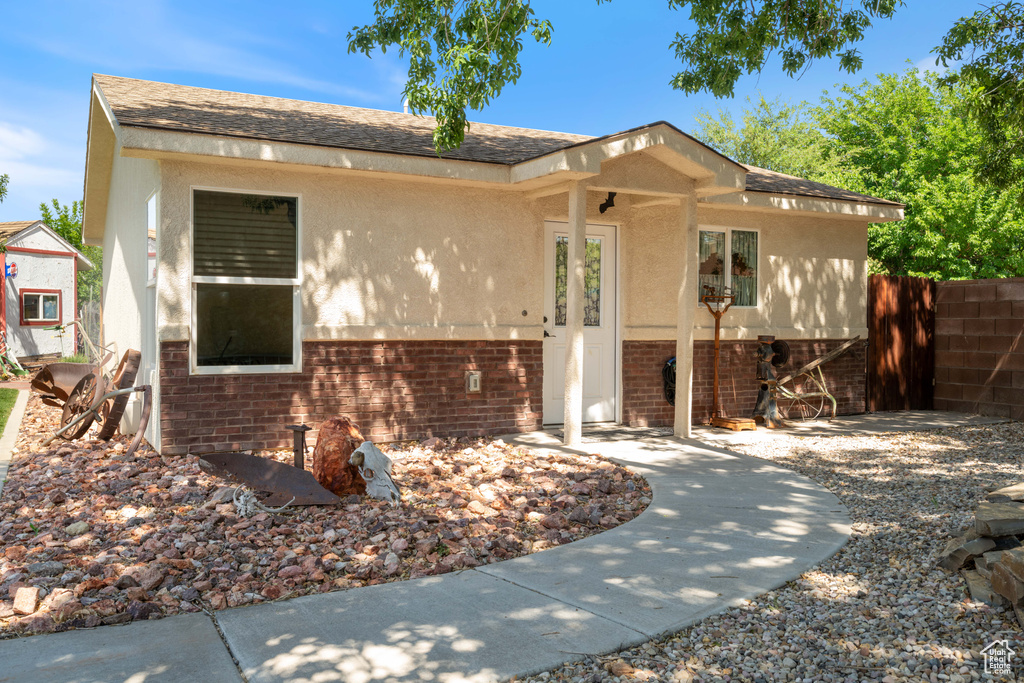 View of front of home with brick siding, stucco siding, and roof with shingles