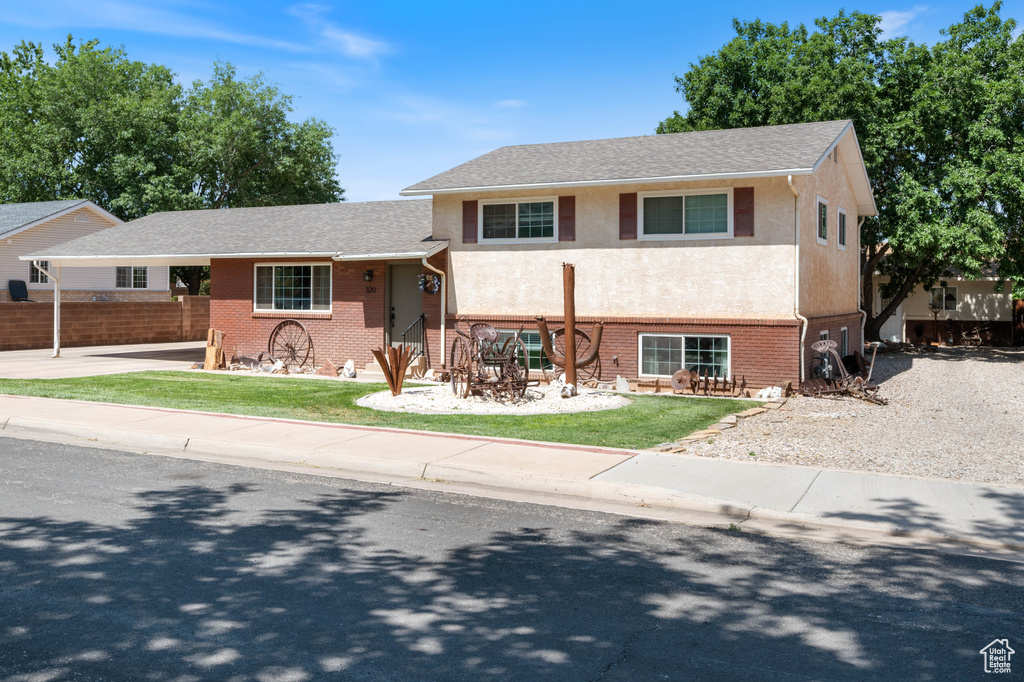 View of front of property with brick siding, stucco siding, driveway, and a carport