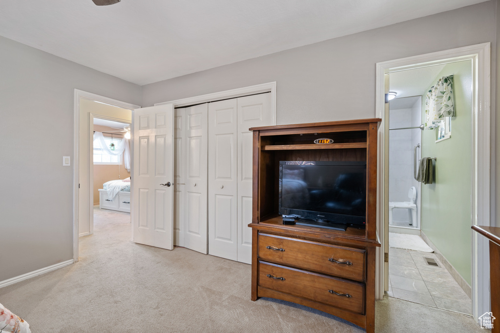 Bedroom featuring light colored carpet, a closet, and ensuite bath