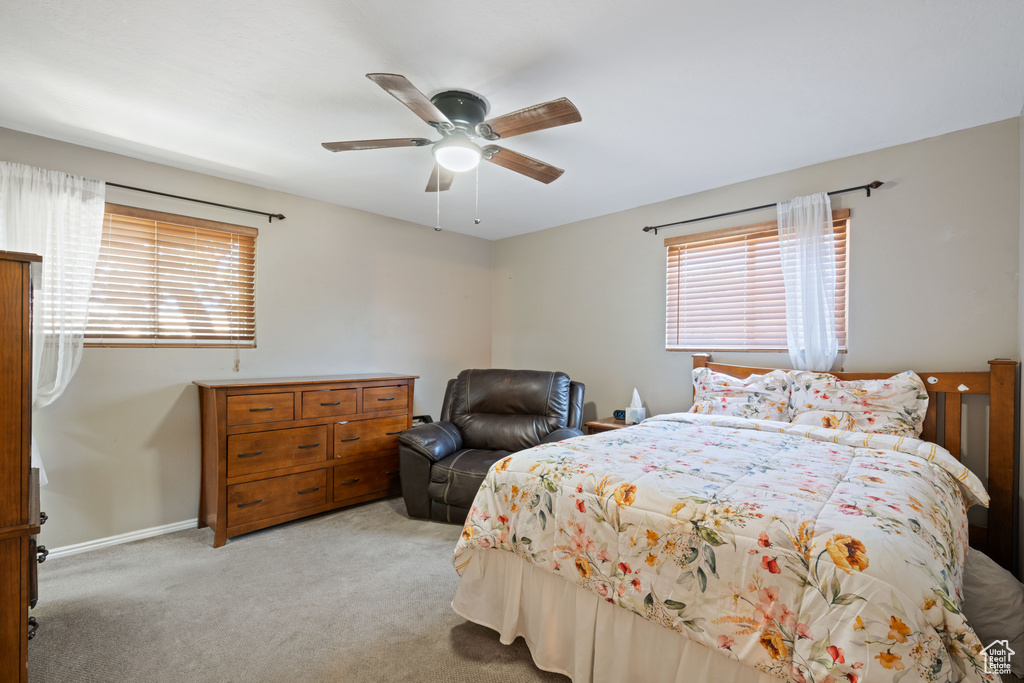 Carpeted bedroom with multiple windows and ceiling fan