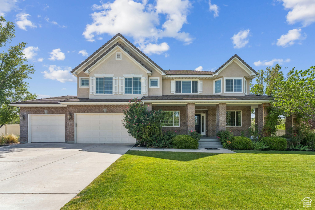 View of front of home featuring concrete driveway, a front lawn, stucco siding, an attached garage, and brick siding