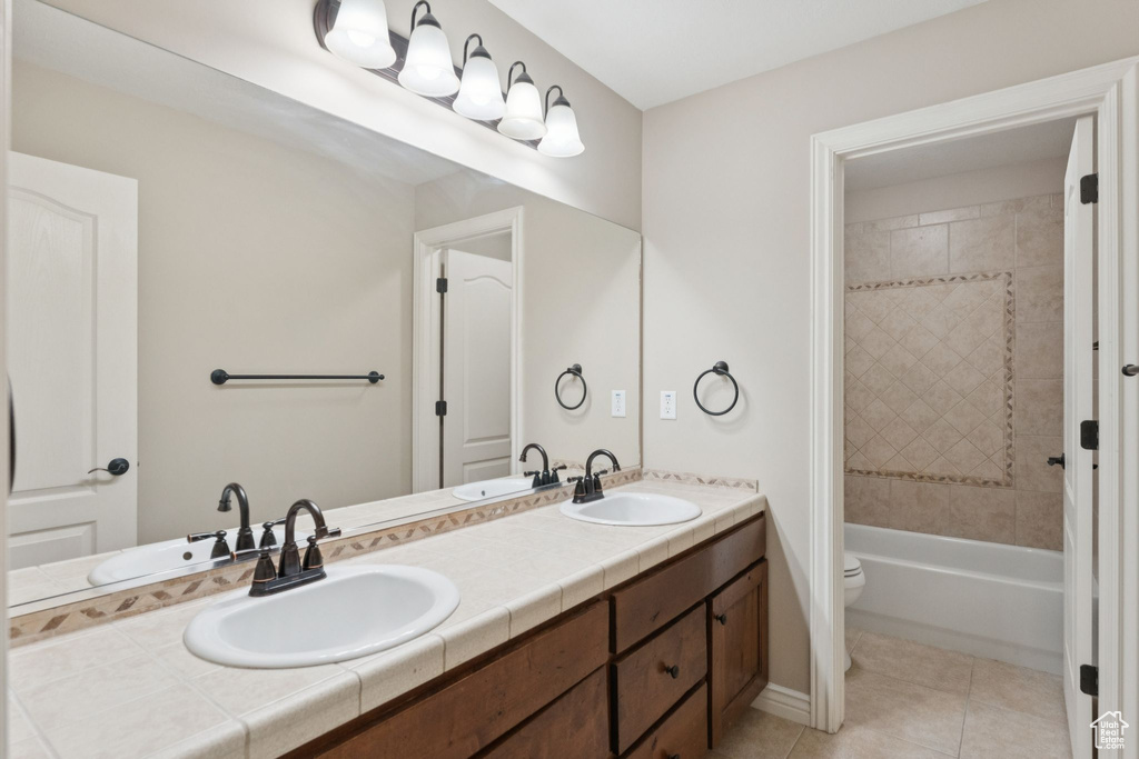Bathroom with double vanity, tile patterned flooring, and tub / shower combination
