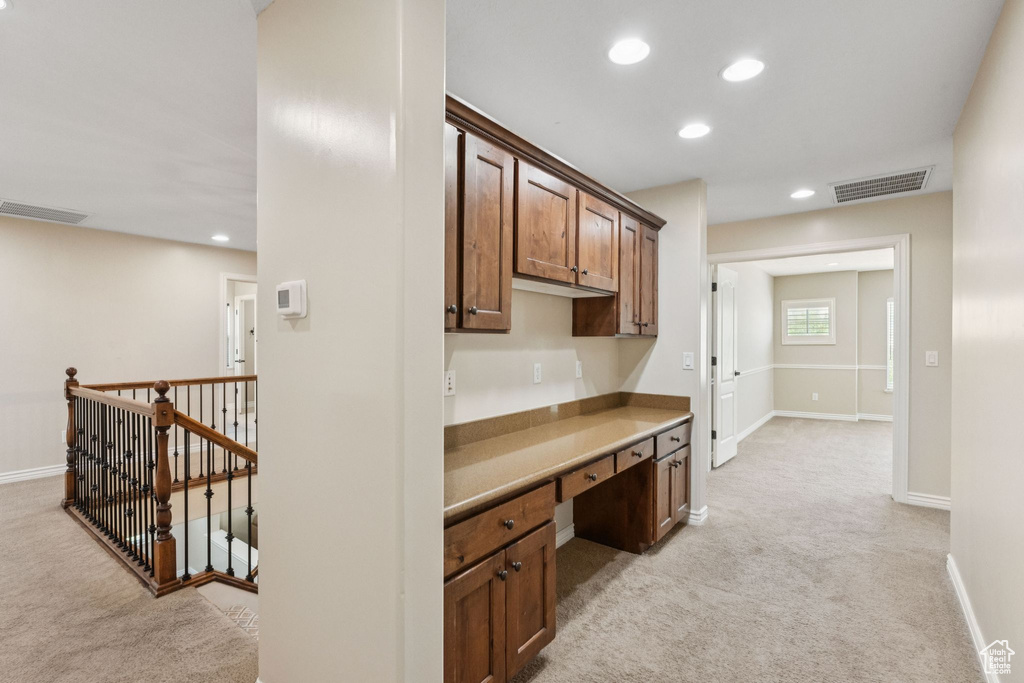 Kitchen featuring light colored carpet, built in study area, recessed lighting, and light countertops