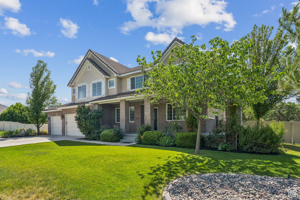 View of front of home with brick siding, driveway, an attached garage, stucco siding, and a porch