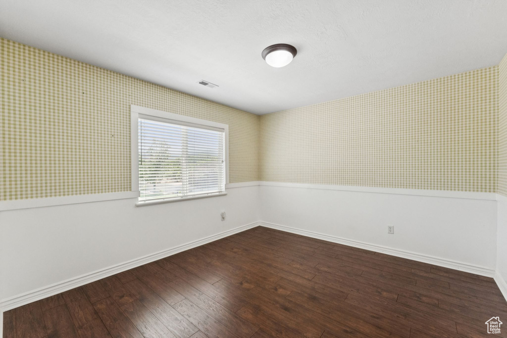 Unfurnished room featuring wallpapered walls and wood-type flooring