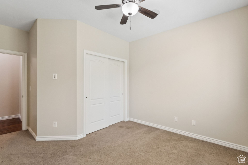 Unfurnished bedroom with carpet floors, a closet, and a ceiling fan