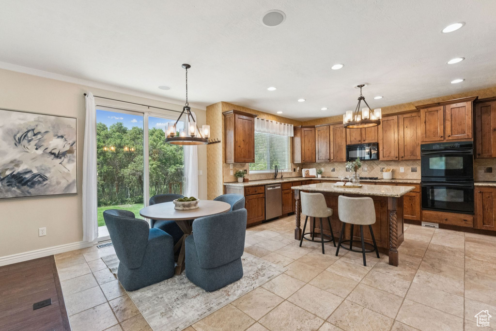 Kitchen with black appliances, a chandelier, tasteful backsplash, brown cabinets, and recessed lighting
