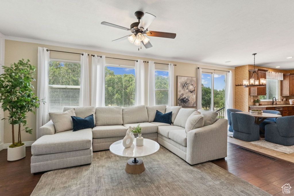 Living area featuring wood finished floors, a chandelier, healthy amount of natural light, and crown molding