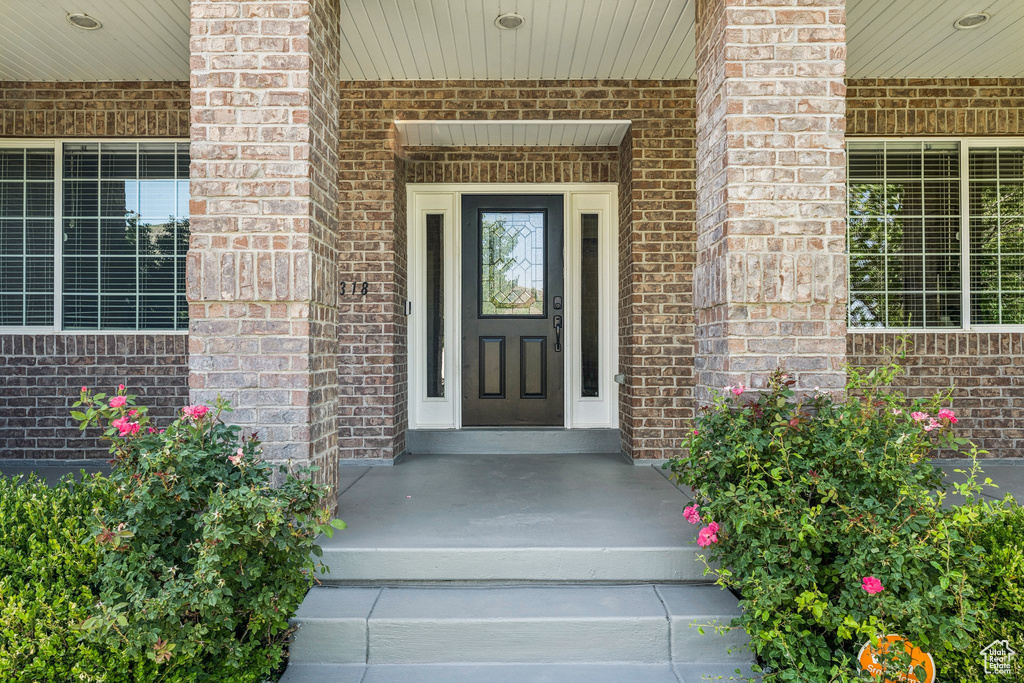 View of exterior entry featuring brick siding and covered porch