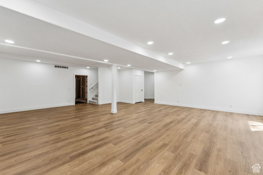Finished below grade area with recessed lighting, stairs, and light wood-style floors