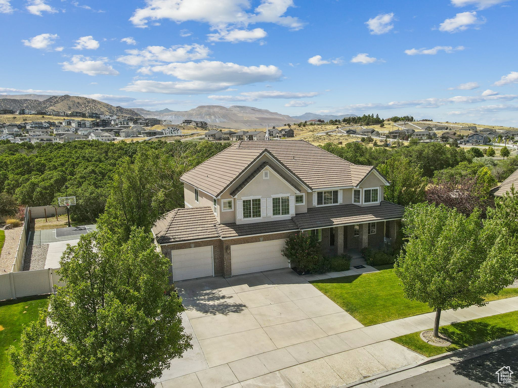 Traditional-style house with a tile roof, a garage, driveway, a mountain view, and brick siding