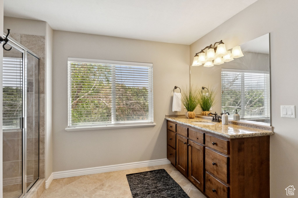 Bathroom with vanity, a tile shower, and tile patterned flooring