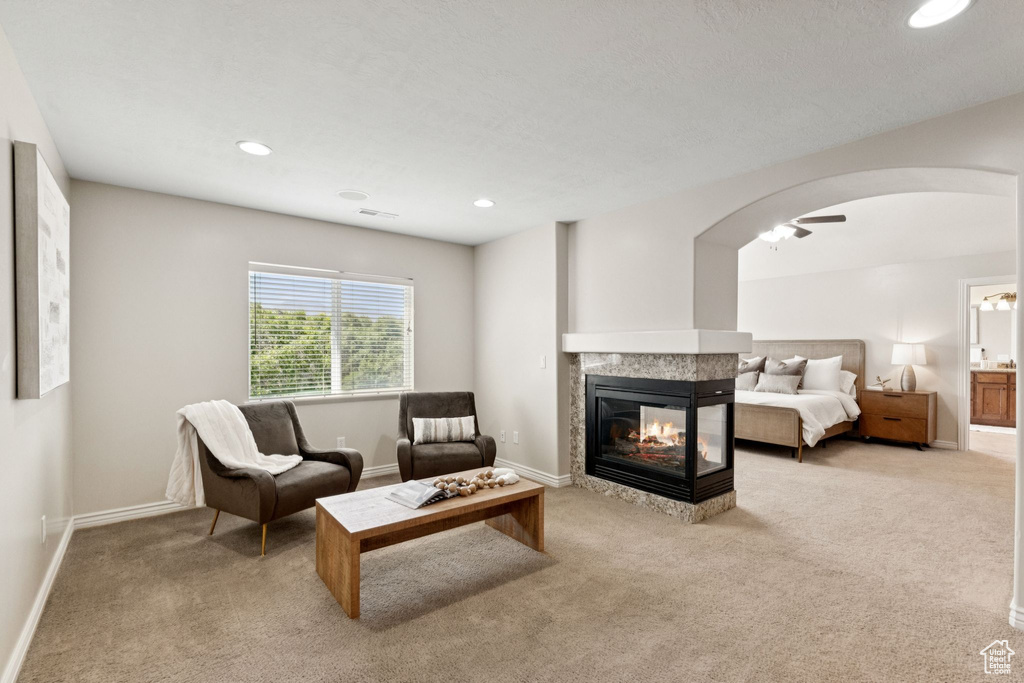 Carpeted living area featuring arched walkways, a multi sided fireplace, and recessed lighting