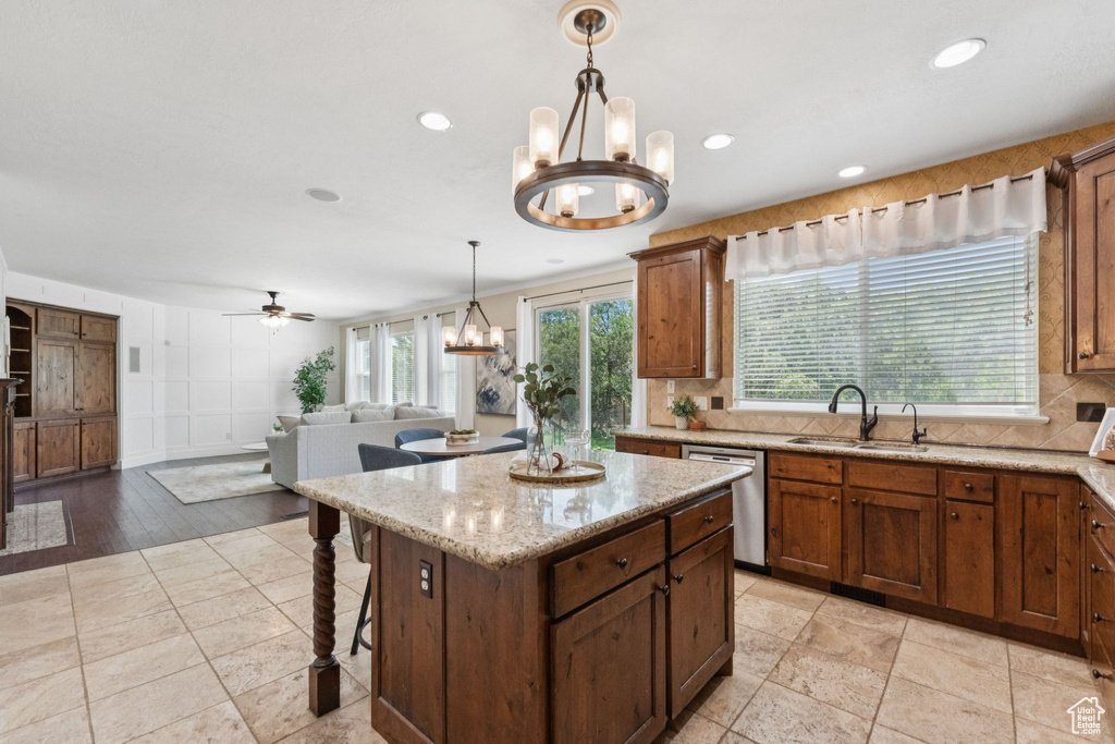 Kitchen with stainless steel dishwasher, a chandelier, decorative backsplash, decorative light fixtures, and a kitchen island