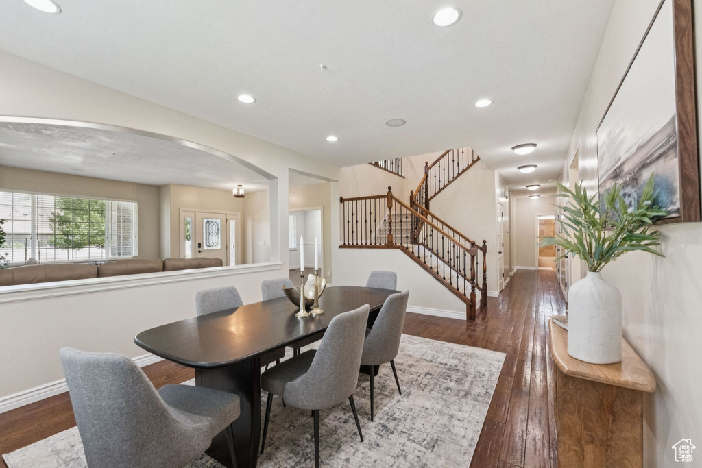 Dining space with arched walkways, stairway, dark wood-type flooring, and recessed lighting