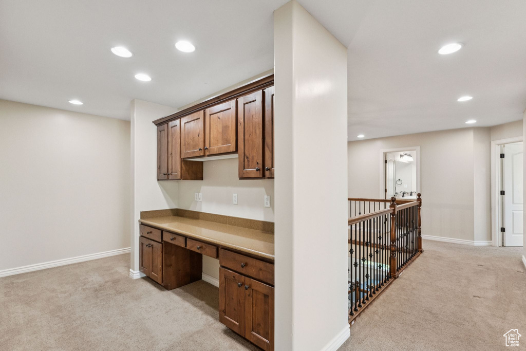 Kitchen featuring light colored carpet, built in desk, recessed lighting, and light countertops