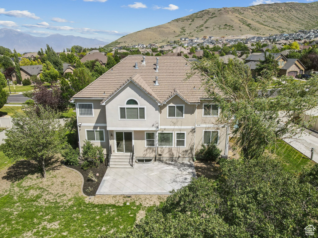 Rear view of house with stucco siding, a patio area, a residential view, and a mountain view