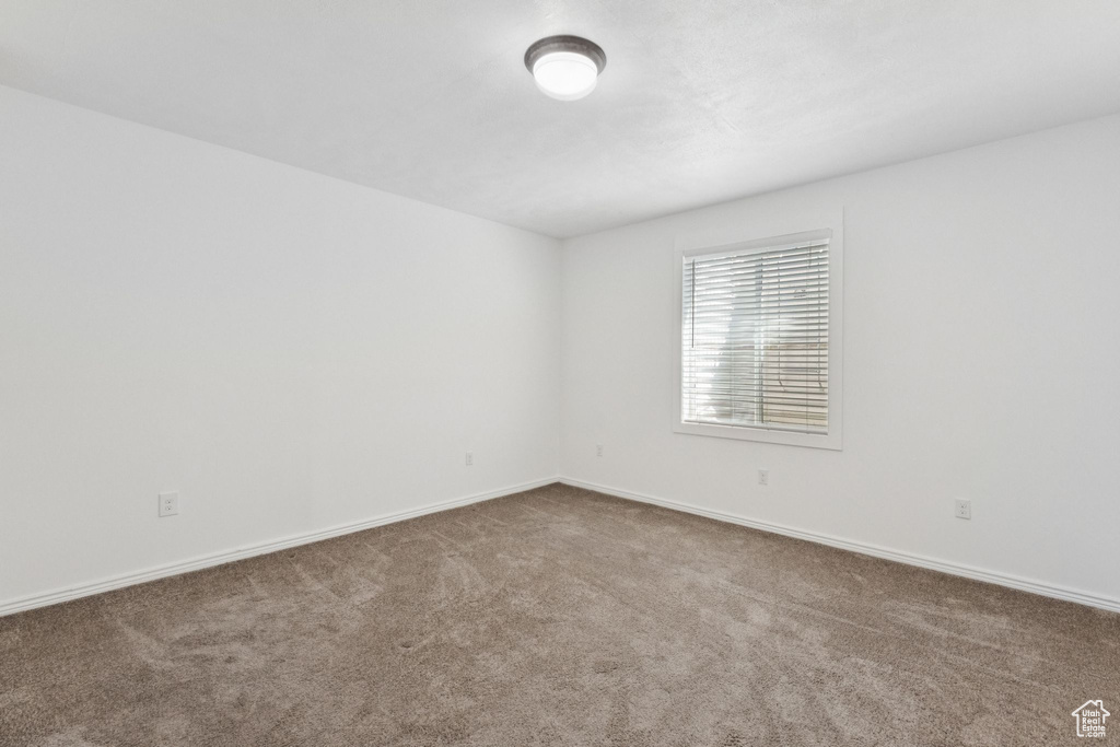 Carpeted spare room featuring baseboards