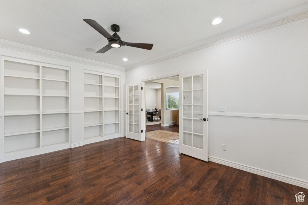 Unfurnished room featuring french doors, ornamental molding, wood finished floors, built in shelves, and a ceiling fan