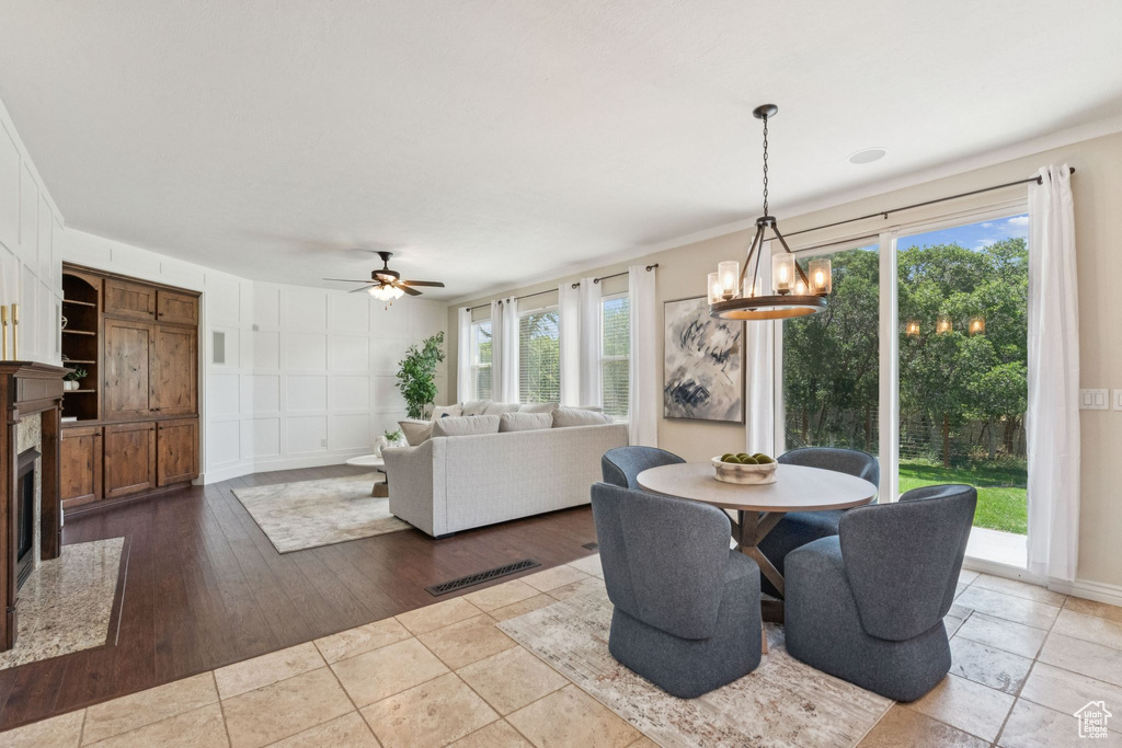 Dining space with plenty of natural light, ceiling fan, a high end fireplace, a chandelier, and crown molding