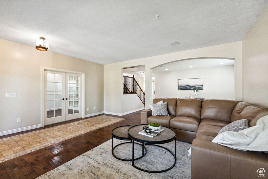 Living area featuring arched walkways, hardwood / wood-style floors, stairs, french doors, and recessed lighting