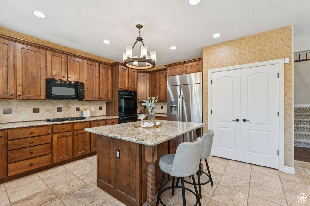 Kitchen with black appliances, brown cabinetry, a center island, a chandelier, and recessed lighting